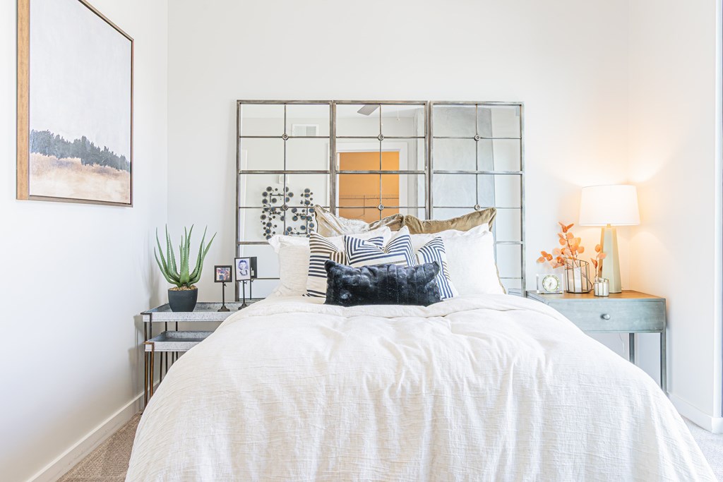 A bedroom with a white bed and a painting on the wall.