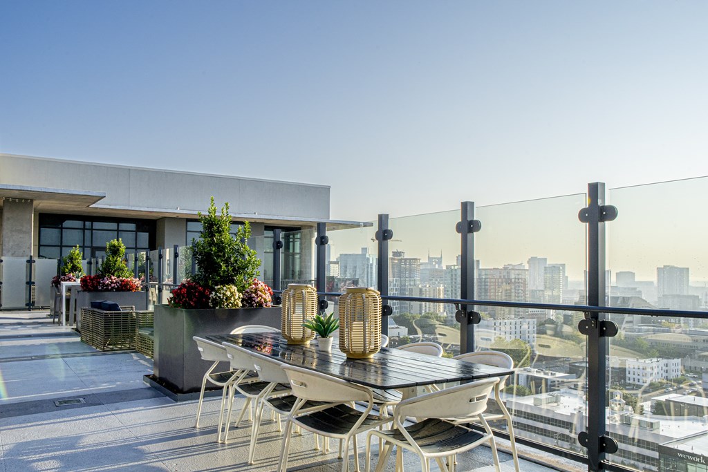 A balcony with a table and chairs overlooking a cityscape.