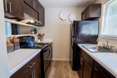 A kitchen with dark wood cabinets and black appliances.