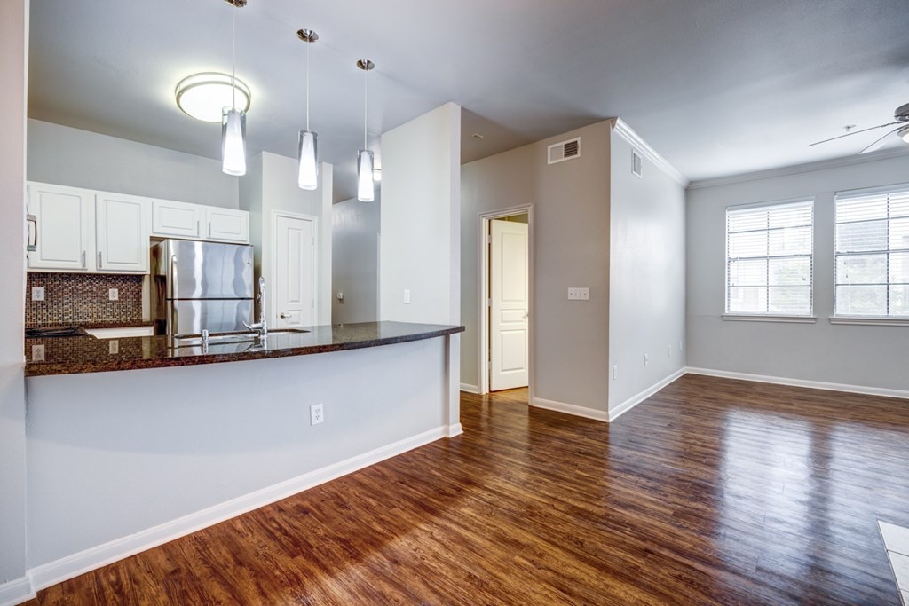 A kitchen with white cabinets and a wooden floor.