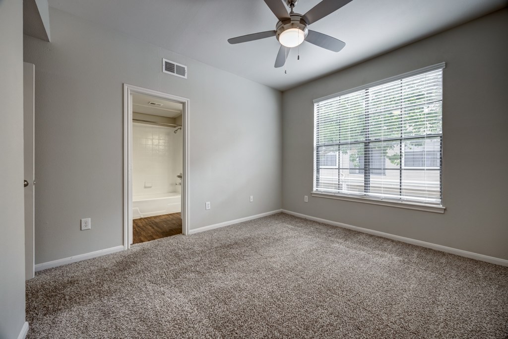 A bedroom with a ceiling fan and a window with blinds.