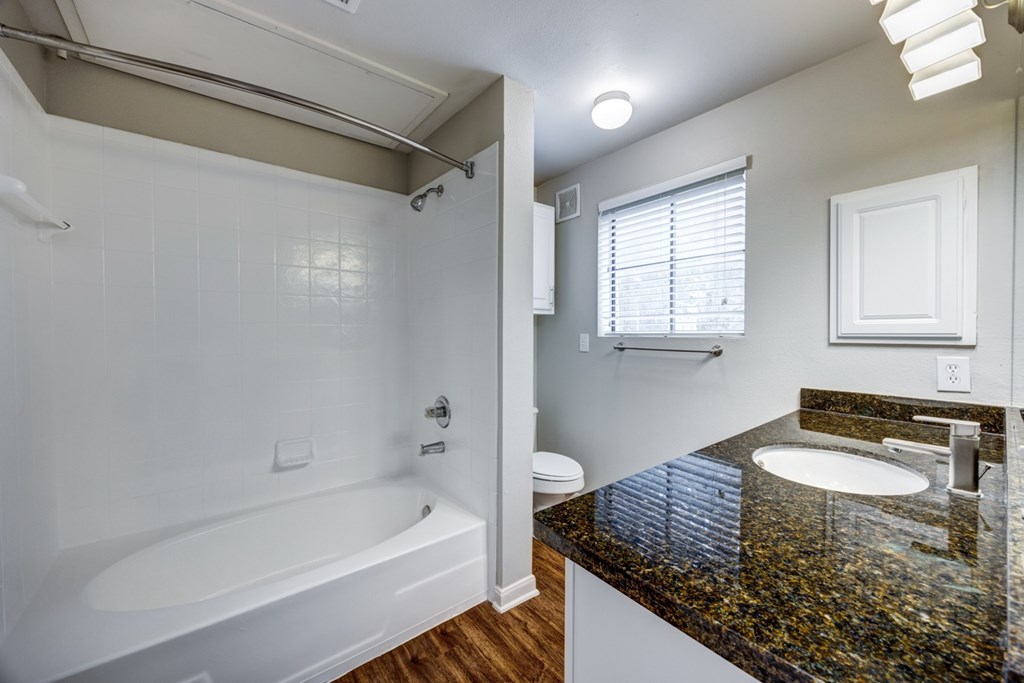 A white bathroom with a black granite counter top.