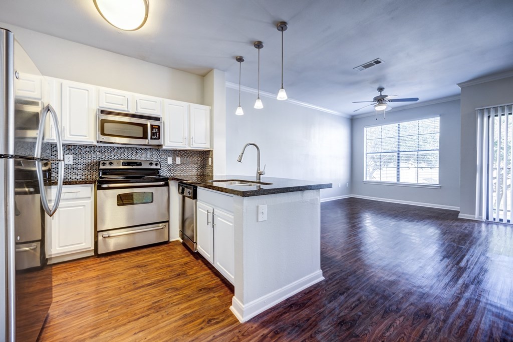 A kitchen with white cabinets and a wooden floor.