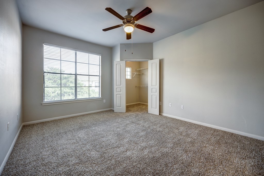A bedroom with a ceiling fan and carpeted floor.