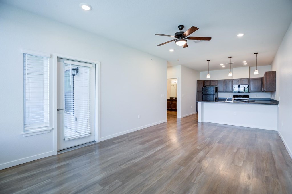 Large living room with a ceiling fan and wooden flooring.