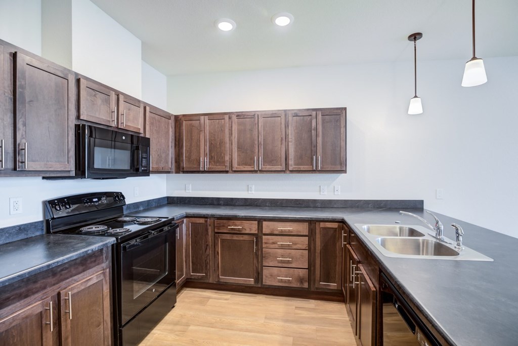 A kitchen with dark wood cabinets and a black stove top oven.