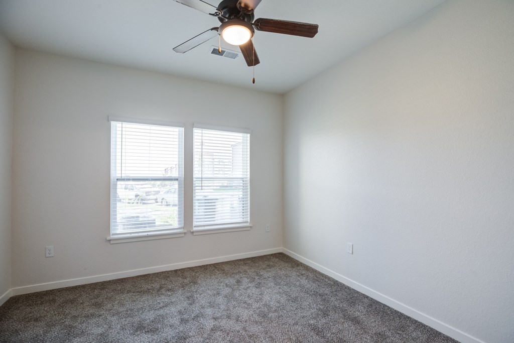 Bedroom with a ceiling fan and carpeted floor.