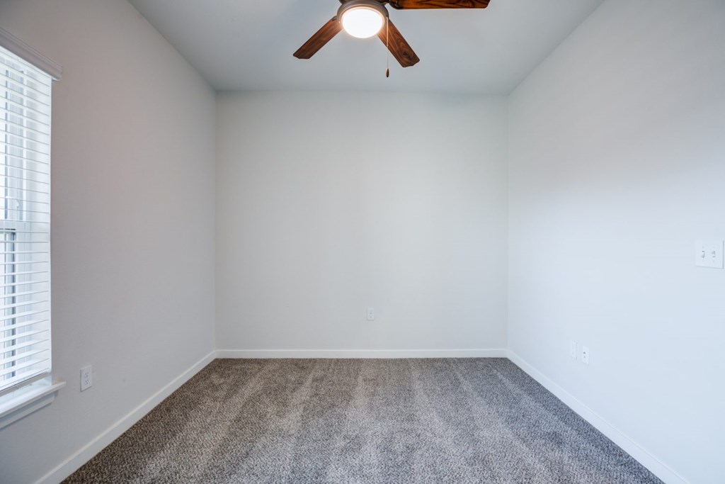 A large  bedroom with a ceiling fan and carpeted floor.