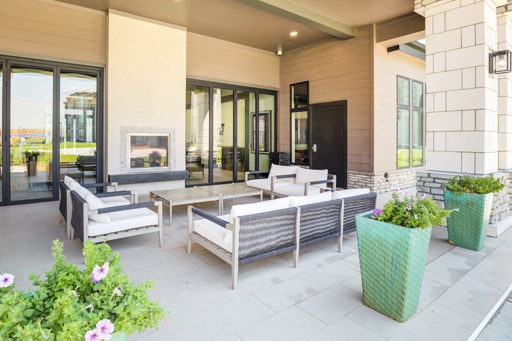 A patio with a couch, chairs, and potted plants.