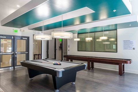 a game room with a pool table and pendant lights