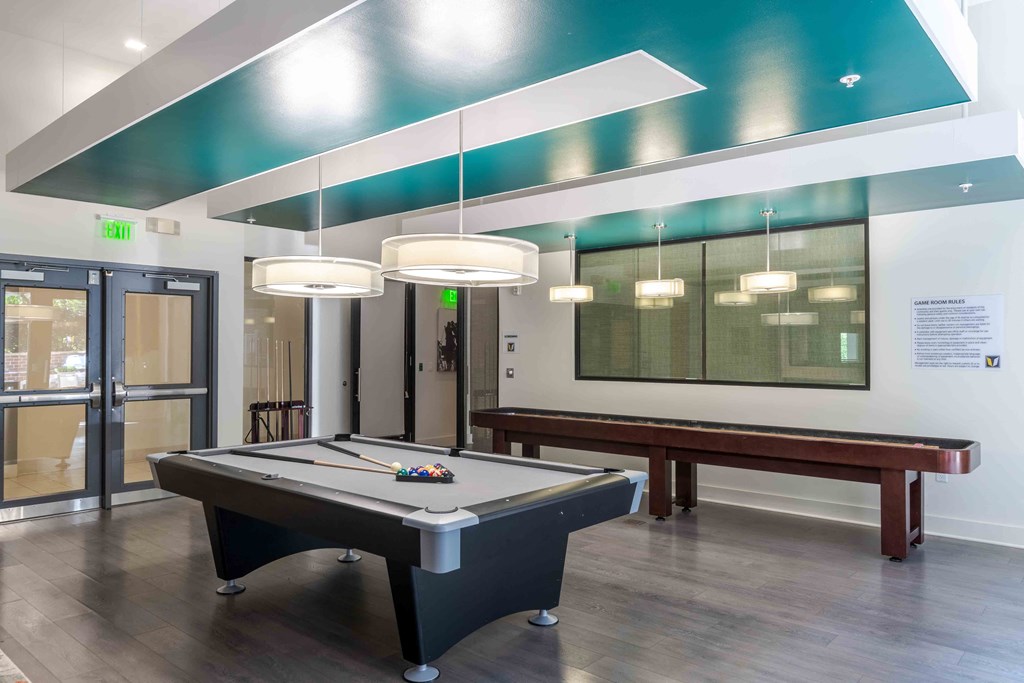 a game room with a pool table and pendant lights