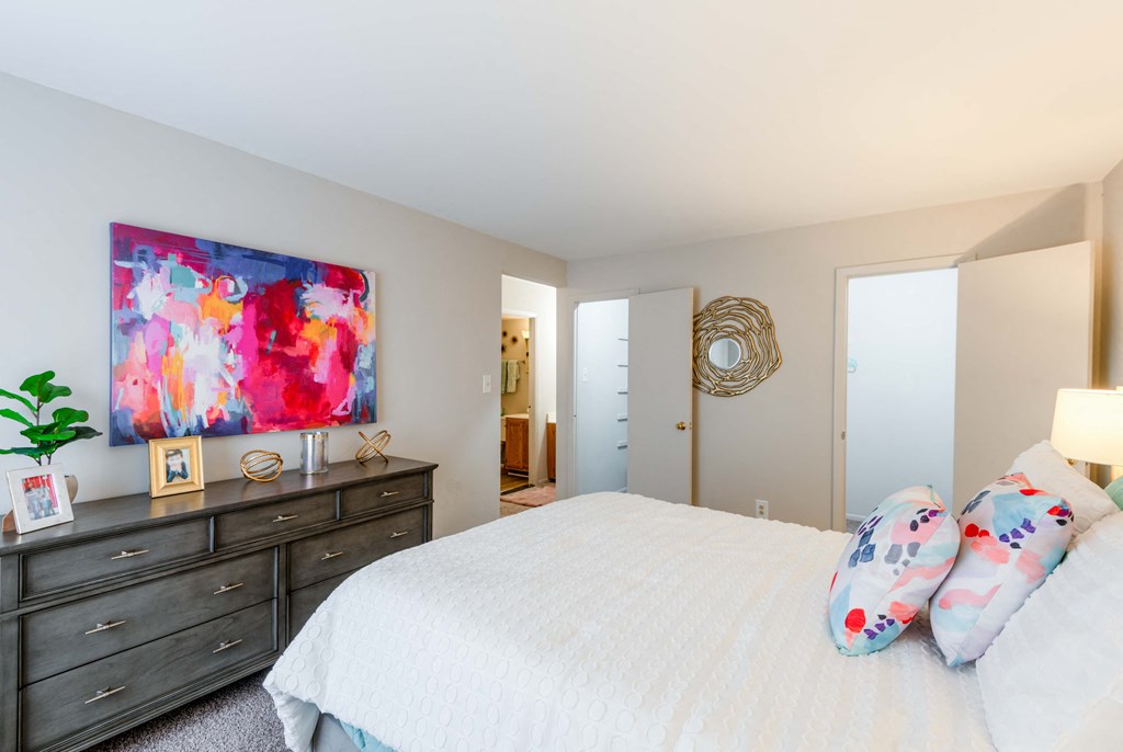 a bedroom with a white bed and a painting on the wall