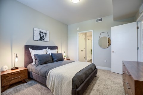 A bedroom with a bed, nightstand, and a mirror on the wall.