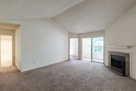 an empty living room with a fireplace and a sliding glass door