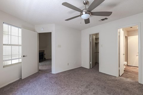 an empty bedoom with a ceiling fan and a door to a bedroom
