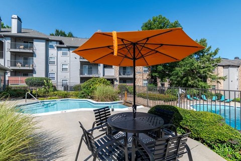 our apartments have a pool and a patio with chairs and an umbrella
