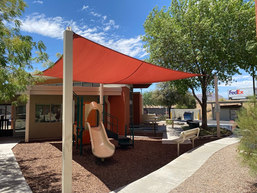a playground with a swing set and a red awning