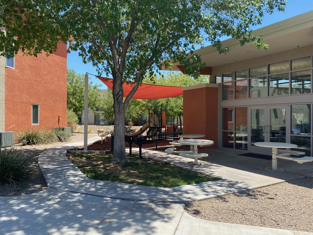 a courtyard in front of a building with tables and a tree