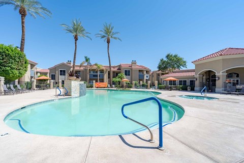 A swimming pool surrounded by palm trees and apartment buildings.