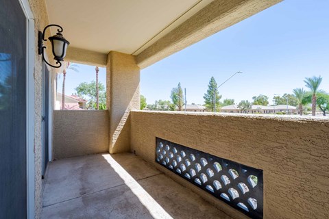 A balcony with a wall-mounted light fixture and a decorative grate.