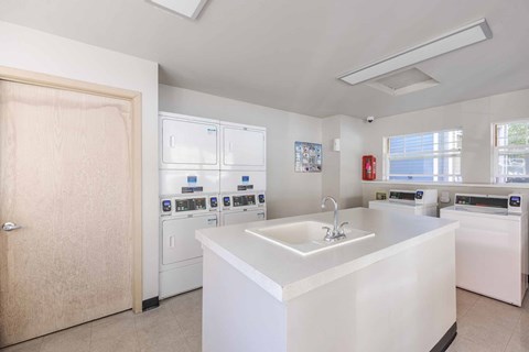 A white kitchen with a sink and a washing machine.