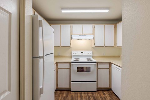 A kitchen with white appliances and wooden floors.
