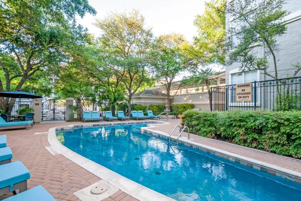a swimming pool with chairs and a building in the background