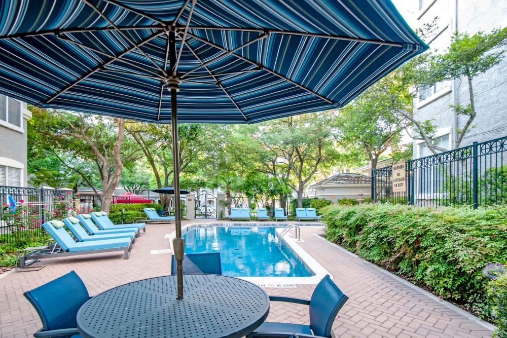 a swimming pool with a table and chairs under an umbrella