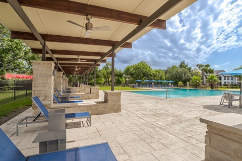 a covered bbq area at the swimming pool of the apartment complex