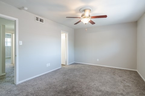 an empty living room with a ceiling fan