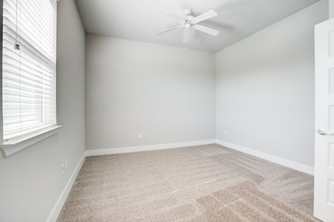 Carpeted bedroom with ceiling fan and window
