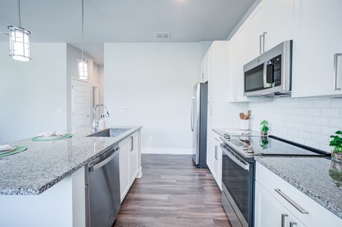 A modern kitchen with granite countertops and stainless steel appliances.