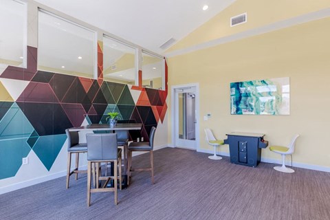 a dining room with a table and chairs and a colorful wall