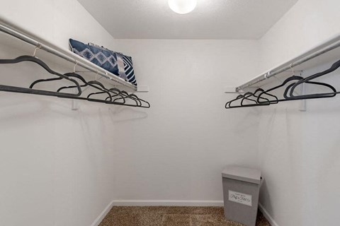 a closet with two hanging racks and a trash can