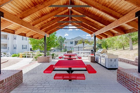 a picnic pavilion with benches and tables under a wooden roof