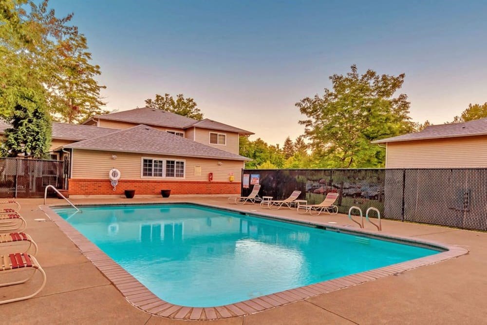 a swimming pool with chairs around it in front of a house