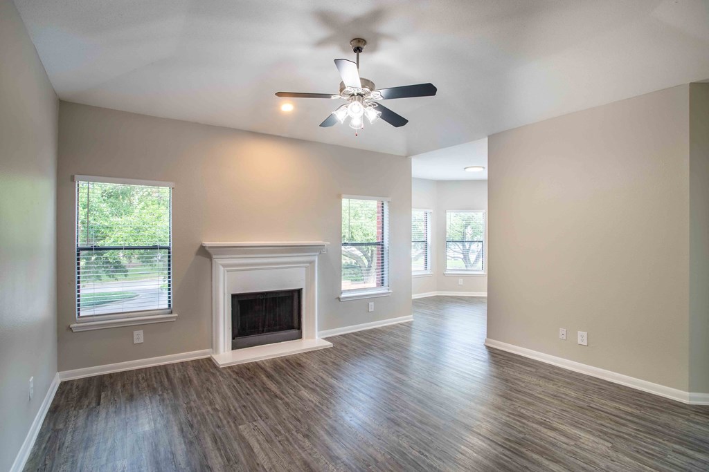 an empty living room with a ceiling fan and a fireplace