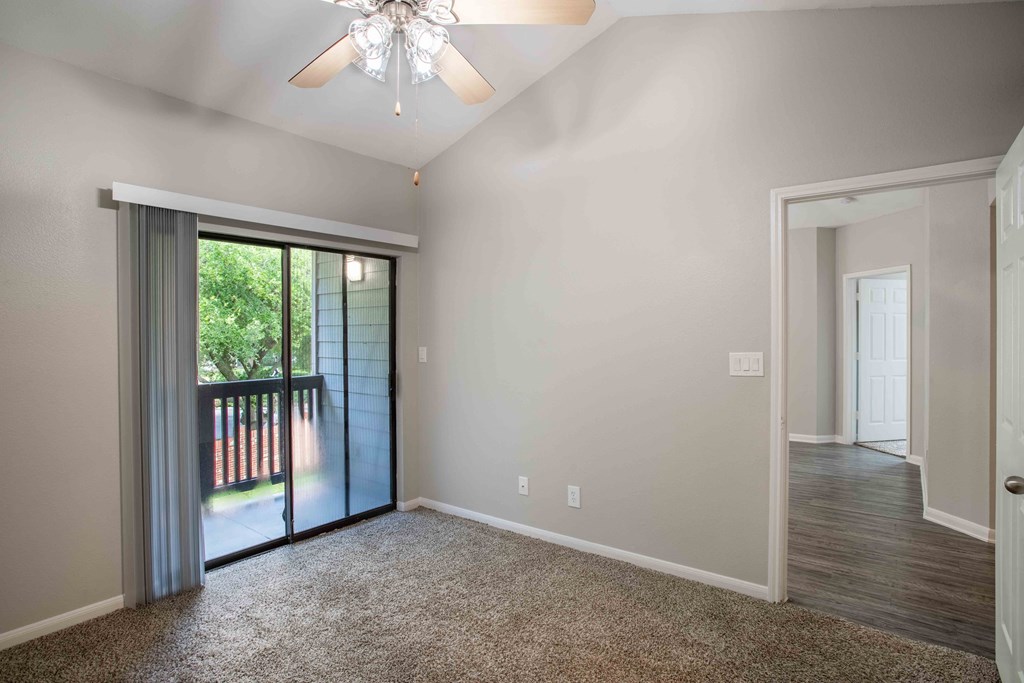 an empty living room with a sliding glass door to a balcony