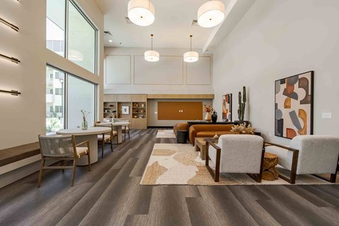 A modern living room with a dining area and a large painting on the wall.