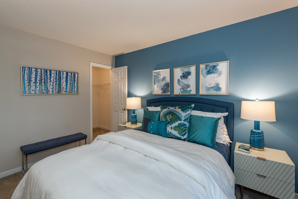 A bedroom with a white bed and blue walls.