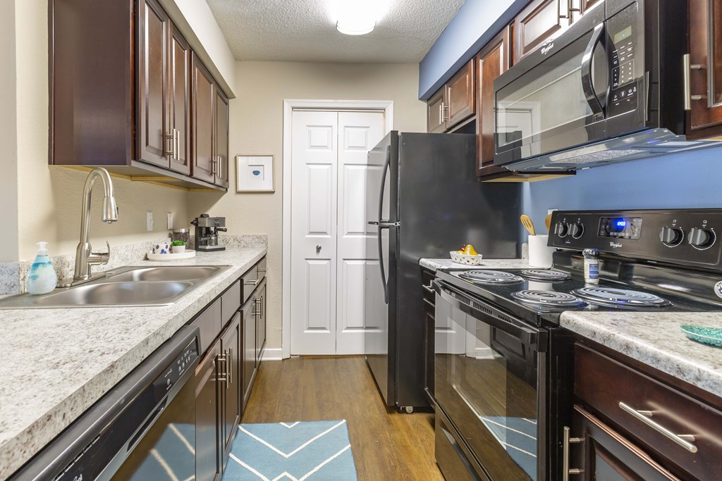 A kitchen with a black refrigerator and stove top oven.