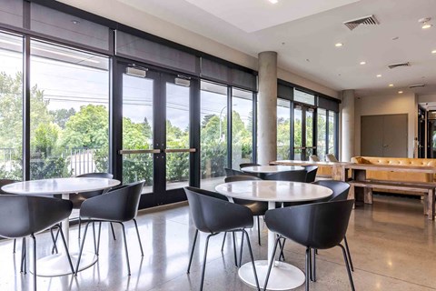 A conference room with a table and chairs and a view of trees outside the window.