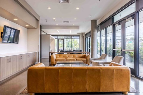 A living room with a brown couch and a painting on the wall.