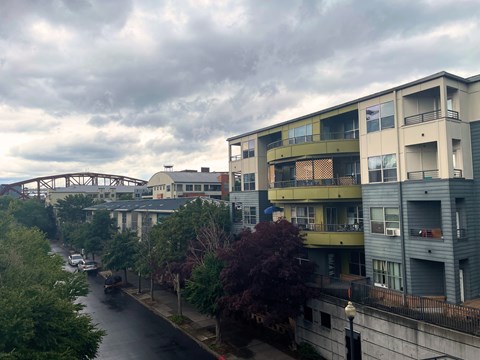 A view of a street with a bridge in the background and apartment buildings on the right.