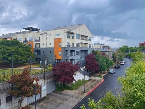 A street view of a residential area with apartment buildings and cars parked on the side of the road.