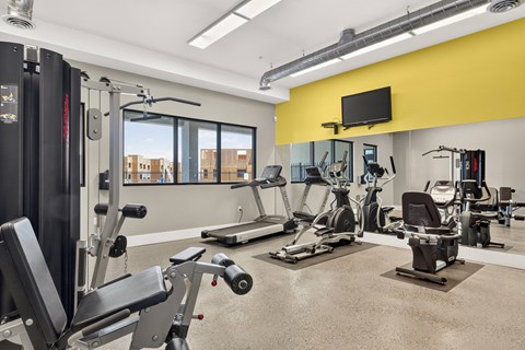 A gym with a variety of equipment including treadmills, weights, and exercise machines.