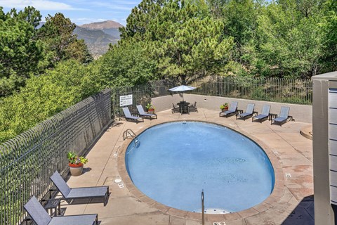 A small round pool surrounded by a fence and chairs.