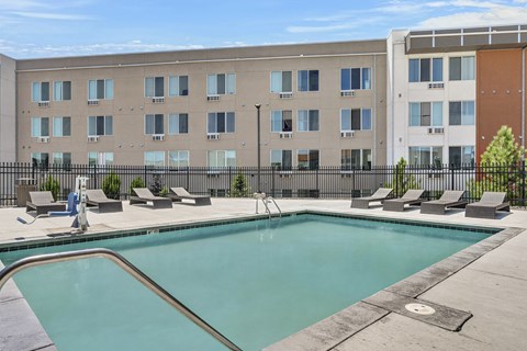 A swimming pool in front of a multi-story apartment building.