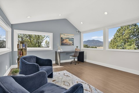 A living room with blue chairs and a painting on the wall.