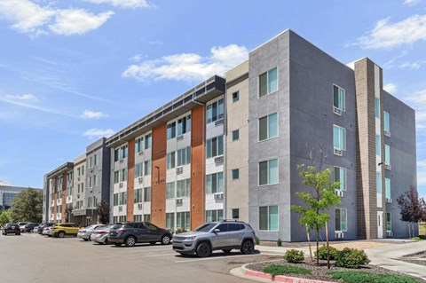 A modern apartment building with a parking lot in front.